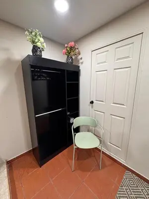 a chair sitting next to a black cabinet with a door at Oasis Urbano San Benito in San Salvador