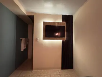 a room with a television on a wall with a hallway at Oasis Urbano San Benito in San Salvador
