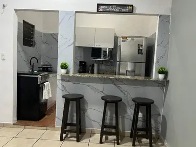 a kitchen with three bar stools and a refrigerator at Oli's apartment studio in Mexicanos