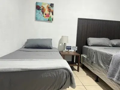 a bedroom with two beds and a picture of a cow at Oli's apartment studio in Mexicanos