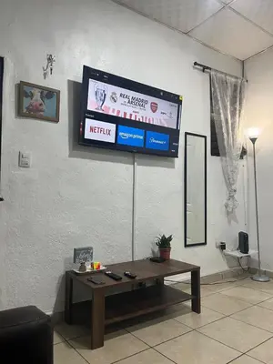 a television on a wall with a table in a room at Oli's apartment studio in Mexicanos