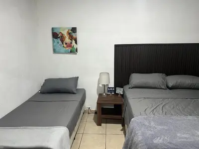 a room with two beds and a table with a picture on the wall at Oli's apartment studio in Mexicanos