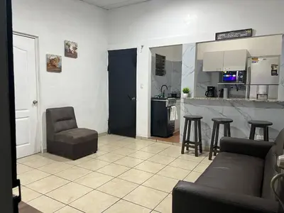 a living room with a couch and chairs and a kitchen at Oli's apartment studio in Mexicanos