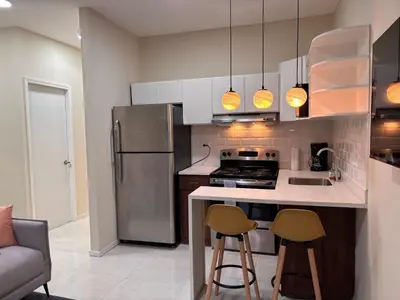 a kitchen with a refrigerator and two bar stools at Apartment in the heart of SA in Santa Ana