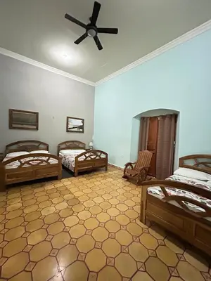 a bedroom with three beds and a ceiling fan at Hostal Vega in Suchitoto
