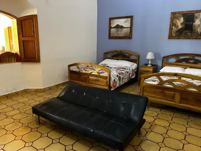 a room with two beds and a bench in it at Hostal Vega in Suchitoto