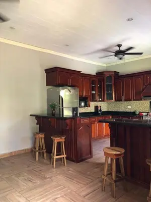 a kitchen with wooden cabinets and bar stools at Hostal Vega in Suchitoto