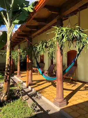 a hammock hanging from a house with palm trees at Hostal Vega in Suchitoto