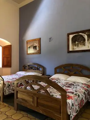 a bedroom with two beds and two pictures on the wall at Hostal Vega in Suchitoto
