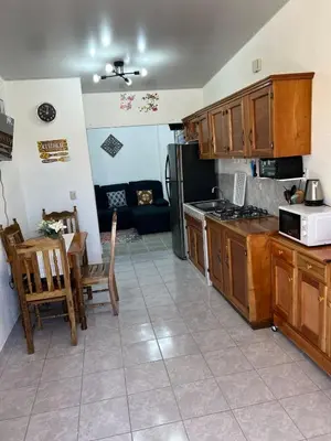 a kitchen with wooden cabinets and a table and a couch at Casa de Descanso en la Villa Panamericana in San Miguel