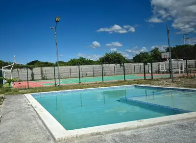 an empty swimming pool in front of a tennis court at Stay with us just 5 minutes from the international airport of El Salvador in Las Flores