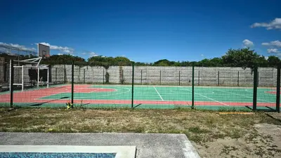 a tennis court with a net on a court at Stay with us just 5 minutes from the international airport of El Salvador in Las Flores