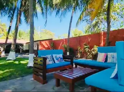 a patio with palm trees and a blue couch and a table at Beachfront- El Torogoz del Pimental in La Esmeralda