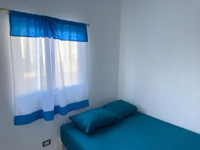a blue bed in a room with a window at Estancia El Torogoz - by Duran in Ahuachapán