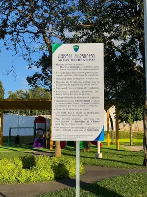 a sign in a park with a playground in the background at Estancia El Torogoz - by Duran in Ahuachapán
