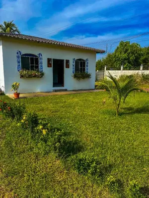 a white house with flowers in a yard at Tres Cielos Cabañas in San Pedro Masahuat