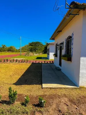 a small white building with a door and a yard at Tres Cielos Cabañas in San Pedro Masahuat
