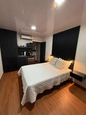 a bedroom with a white bed and a kitchen at VUE by The Cabins in La Libertad