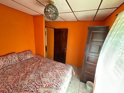 a bedroom with orange walls and a bed and a door at Casa de Montaña en Los Naranjos in Los Naranjos
