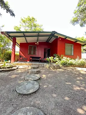 a red house with a table and chairs in front of it at Casa de Montaña en Los Naranjos in Los Naranjos