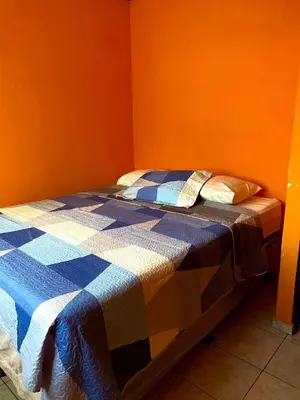 a bed in a room with an orange wall at Casa de Montaña en Los Naranjos in Los Naranjos