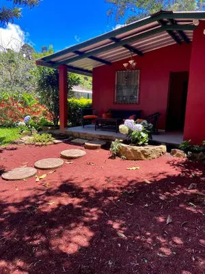 a red house with a picnic table and a bench at Casa de Montaña en Los Naranjos in Los Naranjos
