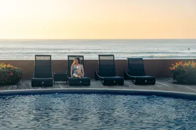 a woman sitting in chairs next to a swimming pool at Casa de Mar Hotel And Villas in La Libertad