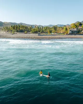 two people sitting on surfboards in the water at Casa de Mar Hotel And Villas in La Libertad