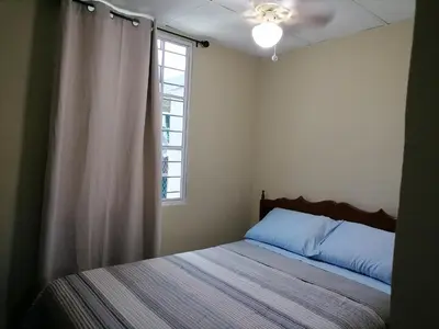 a bed in a bedroom with a window and a curtain at Casa en zona privada in San Salvador