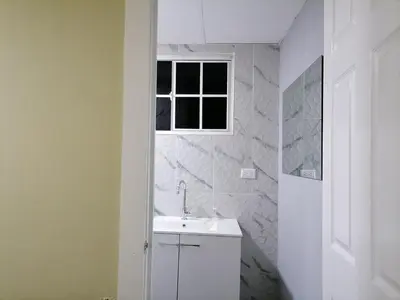 a white bathroom with a sink and a window at Casa en zona privada in San Salvador