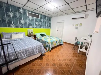 a bedroom with two beds and a desk in it at Tunco Bambú Room 1 in Tamanique