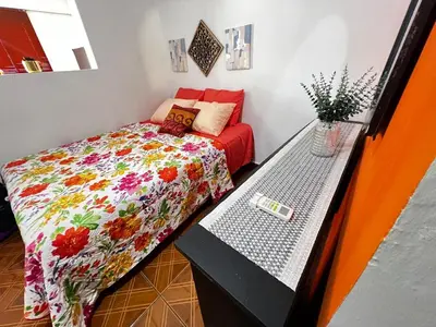 a small bedroom with a bed and a table at Tunco Sun Room 2 in Tamanique