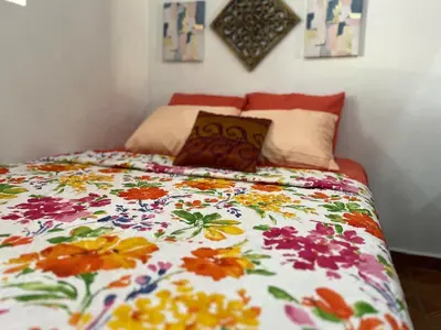 a bed with a colorful comforter and pillows on it at Tunco Sun Room 2 in Tamanique