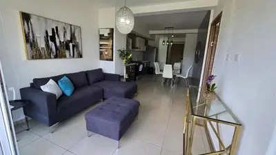 a living room with a couch and a dining room at Acogedor y Centrico Apartamento in San Salvador