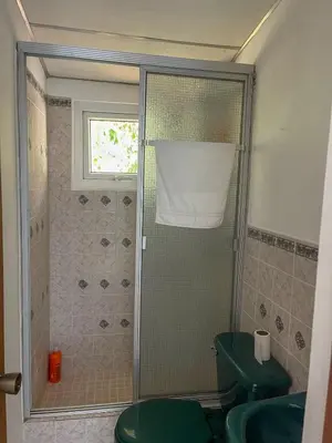 a bathroom with a shower with a green toilet at Casa Tropical Kaylani in Tamanique