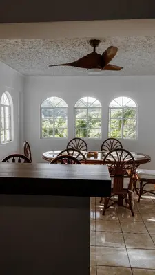 a dining room with tables and chairs and windows at Casa Tropical Kaylani in Tamanique