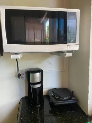 a coffee maker under a microwave on a counter at Cuarto estudio HERSOR in San Salvador