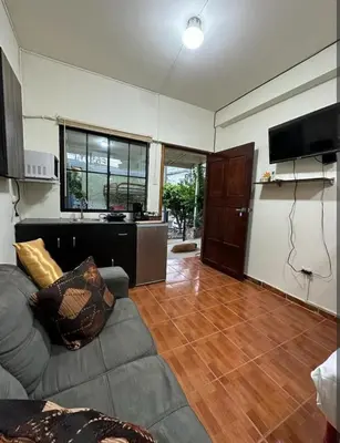 a living room with a gray couch and a kitchen at Cuarto estudio HERSOR in San Salvador