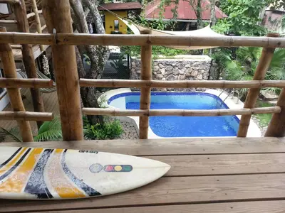 a surfboard sitting on a wooden table next to a pool at Eco del Mar in La Libertad