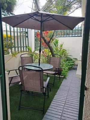 a table and chairs under an umbrella on a patio at La Cima House-Studio in San Salvador