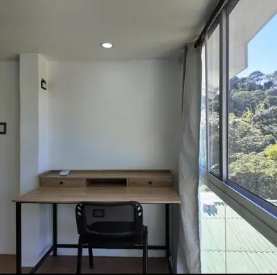 a desk with a chair in a room with a window at Las Terrazas Suites Studio Apartment in San Salvador