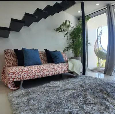 a couch sitting in a living room with a rug at Las Terrazas Suites Studio Apartment in San Salvador