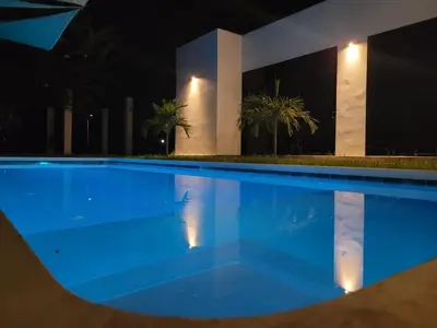 a large blue swimming pool in front of a building at night at Residence in Salinitas, Los Cobanos in Los Cóbanos