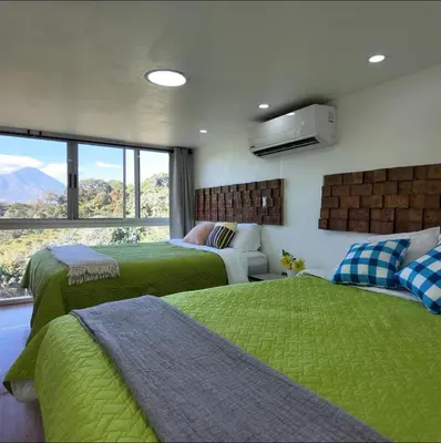 a bedroom with two beds with green sheets and a window at Las Terrazas Suites Studio-type apartment in San Salvador