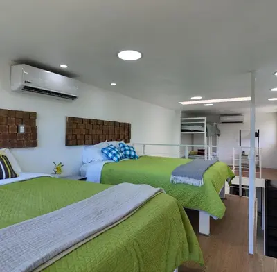 two beds in a room with green blankets at Las Terrazas Suites Studio-type apartment in San Salvador