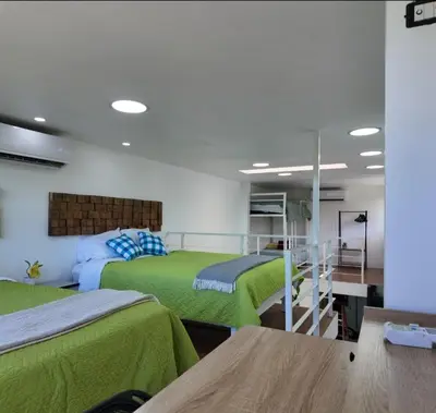 two beds in a room with green sheets at Las Terrazas Suites Studio-type apartment in San Salvador