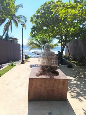 a statue of a person sitting on a bench overlooking the ocean at Zonte Rooftide Studio in ChiltiupÃ¡n