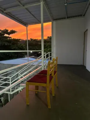 a wooden chair sitting on a balcony with a sunset at Tu Estancia en Sonsonate in Sonsonate