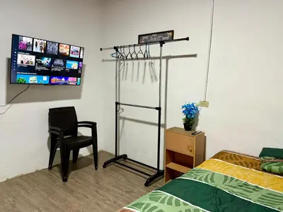 a bedroom with a bed and a chair and a tv at Tu Estancia en Sonsonate in Sonsonate