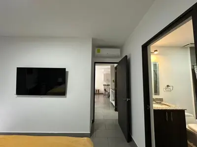 a room with a television on the wall and a hallway at Apartamento amueblado Condado Santa Rosa Santa Tecla La Libertad in Nanastepeque